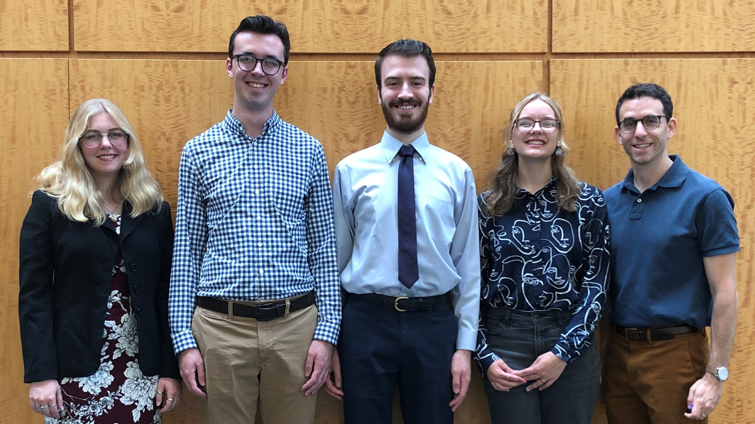 Four students and one professor lined up against a wall for a photo